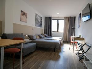 uma sala de estar com duas camas e um sofá em Alianza Suites em Madri
