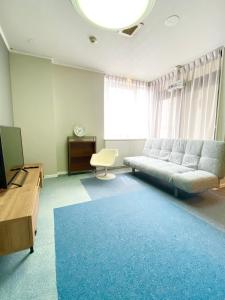 ROSE ROOM في فوكوياما: غرفة معيشة مع أريكة وسجادة زرقاء