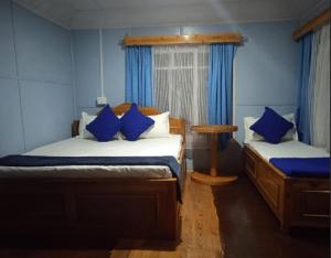2 camas en una habitación con paredes azules y cortinas azules en Kapchakays Farmstay by StayApart, en Kalimpong