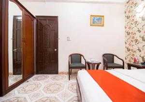 een slaapkamer met een bed en 2 stoelen en een deur bij Tan Hoang Long Hotel in Ho Chi Minh-stad