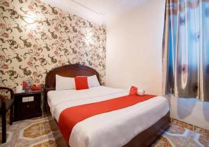 1 dormitorio con 1 cama con sábanas rojas y blancas en Tan Hoang Long Hotel, en Ho Chi Minh