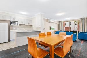 cocina y comedor con mesa de madera y sillas en APX Parramatta, en Sídney