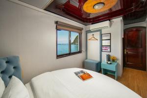 a bedroom with a bed and a window with the ocean at Halong Fantasea Cruise in Ha Long