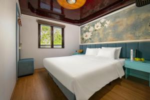 Un dormitorio con una gran cama blanca y una pintura en Halong Fantasea Cruise, en Ha Long