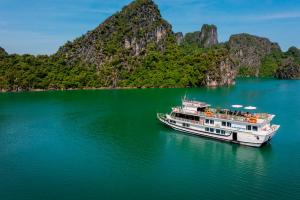 a boat in the water with mountains in the background at Halong Fantasea Cruise in Ha Long