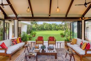 an open living room with a view of a golf course at SaffronStays Elderflower in Alibaug