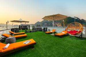 a patio with orange chairs and umbrellas on the grass at Halong Fantasea Cruise in Ha Long