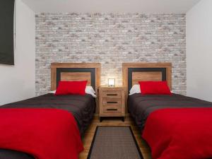 two beds with red pillows in a room with a brick wall at Increibles Vistas Al Valle De Arinsal NY - A Pie De Pistas - Parking Incluido in Arinsal