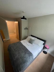 a bedroom with a white bed with a gray blanket at Gatwick Airport Apartment in Crawley
