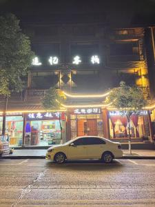 um carro branco estacionado numa rua da cidade à noite em Zhangjiajie Memory Inn em Zhangjiajie