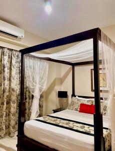 a bedroom with a canopy bed with a red pillow at Pico De Loro 2BR Carola B Unit with Lagoon View in Nasugbu