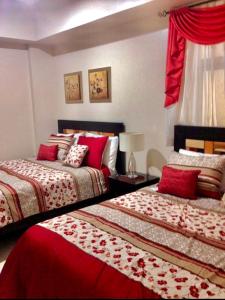 a bedroom with two beds with red and white sheets at Pico De Loro 2BR Carola B Unit with Lagoon View in Nasugbu