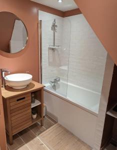 een badkamer met een wastafel en een bad met een spiegel bij Charmante maison 3 chambres avec cour in Lille