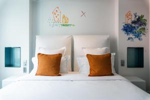 a bedroom with a white bed with orange pillows at 1K Paris in Paris