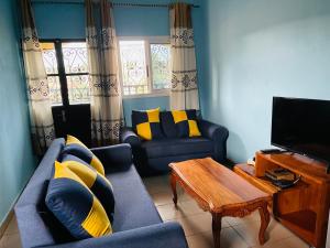 uma sala de estar com sofás azuis e uma televisão em Complexe BEL AIR em Bafoussam