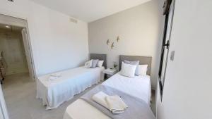 Habitación blanca con 2 camas y espejo. en Amazing 2 Bed 2 Bath Apartment Los Dolses, en Orihuela Costa