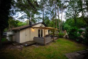 une petite maison avec une terrasse dans une cour dans l'établissement Chalet de bosuil, à Zutendaal