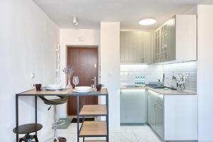 a kitchen with white cabinets and a table and chairs at Olive City View Apartment in Wrocław