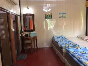 um quarto com uma cama, uma mesa e um espelho em บ้านปุณยาพร โฮมสเตย์ em Amphawa