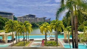 a view of a pool with palm trees and buildings at Pico De Loro 2BR Carola B Unit with Lagoon View in Nasugbu