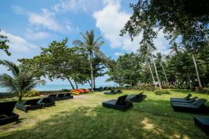 a row of black chairs sitting on the grass near the beach at Blue Bay Resort in Ko Yao Yai