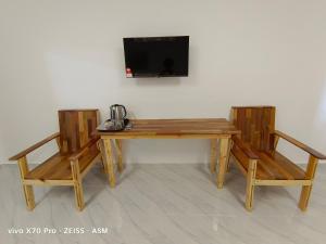 a wooden table with two chairs and a television on a wall at ASM Roomstay-4-2 Queen Beds in Kuala Terengganu