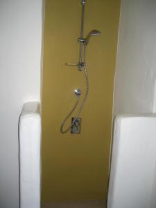 a bathroom with a shower in a yellow wall at Chora Elegant Traditional House in Amorgos +38 photos