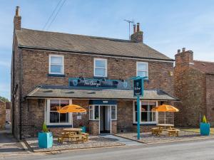 un bâtiment en briques avec des tables et des parasols devant lui dans l'établissement The George Country Inn, Wath, à Wath