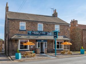 a brick building with tables and umbrellas in front of it at The George Country Inn, Wath in Wath