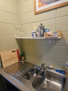 a kitchen counter with a sink and a shelf above it at Di's B&B in Matamata