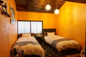 two beds in a room with yellow walls at HOTEL Clam Chowder in Kyoto