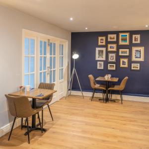 a dining room with two tables and chairs and a blue wall at The George Country Inn, Wath in Wath