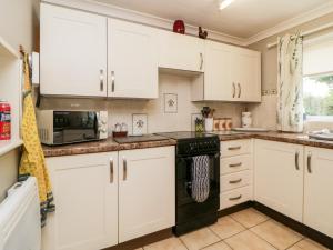 a kitchen with white cabinets and a black stove top oven at Little Claremont in Yelverton
