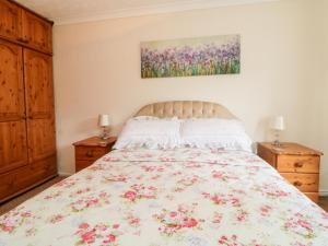 a bedroom with a bed with a floral bedspread at Little Claremont in Yelverton