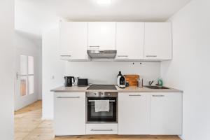 una cocina blanca con armarios y electrodomésticos blancos en Casa Bergstraße 3 en Bensheim