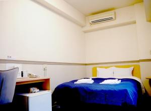1 dormitorio con 1 cama con colcha azul en Business Hotel Legato, en Tokio