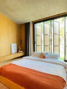 a bedroom with a large bed with a large window at T House Cha-Am 