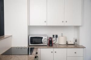 a kitchen with white cabinets and a microwave on a counter at Quattro Beachfront Sea View Ap 53 in Larnaka