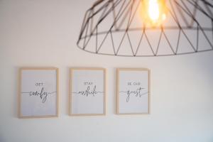 three framed photos on a white wall with a chandelier at Quattro Beachfront Sea View Ap 53 in Larnaka