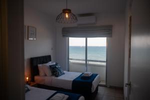 a room with two beds and a window with the ocean at Quattro Beachfront Sea View Ap 53 in Larnaka