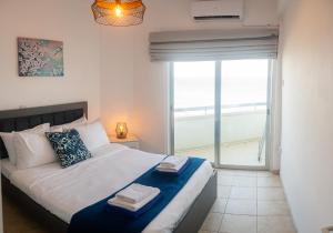 a bedroom with a large bed with a large window at Quattro Beachfront Sea View Ap 53 in Larnaka
