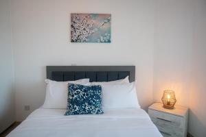 a bedroom with a white bed with a blue pillow at Quattro Beachfront Sea View Ap 53 in Larnaka