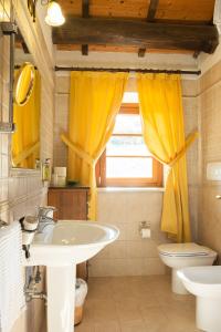 a bathroom with a sink and a toilet and yellow curtains at Country House Il Cascinale in Colonnella