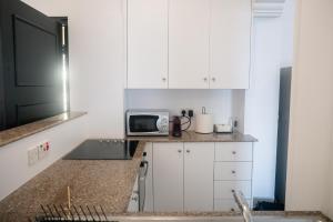 a kitchen with white cabinets and a microwave at Quattro Beachfront Sea View Ap 53 in Larnaka