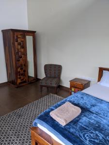 1 dormitorio con 1 cama con manta azul y silla en Moksha Infinity Valley, en Kotagiri