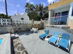 eine Terrasse mit zwei blauen Stühlen sowie einem Tisch und Stühlen in der Unterkunft Los Nidos in San Bartolomé de Tirajana