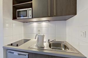 a kitchen with a sink and a microwave at City Résidence Tours in Tours