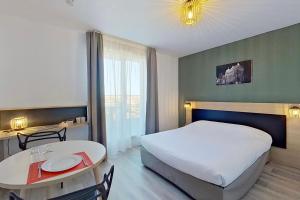 City Résidence Tours في تور: غرفة فندقية بسرير كبير وطاولة