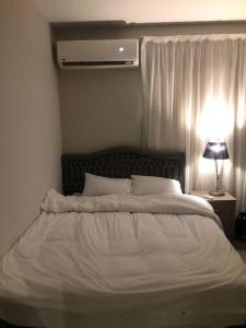 a white bed in a bedroom with a lamp at Lovely studio in the heart of heliopolis, cairo in Cairo