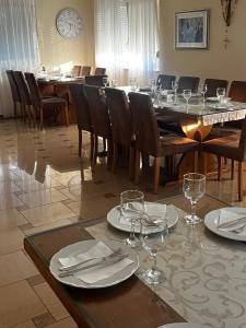 uma sala de jantar com uma mesa com pratos e copos de vinho em Rooms Ante em Međugorje
